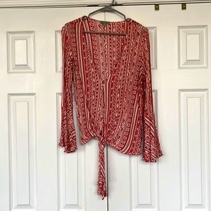 Burnt orange Aztec print bell sleeved blouse. Deep V neck. Blouse ties at bottom